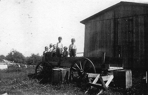 The Gagnon boys and a friend on wagon next to barn at the farm in 1947